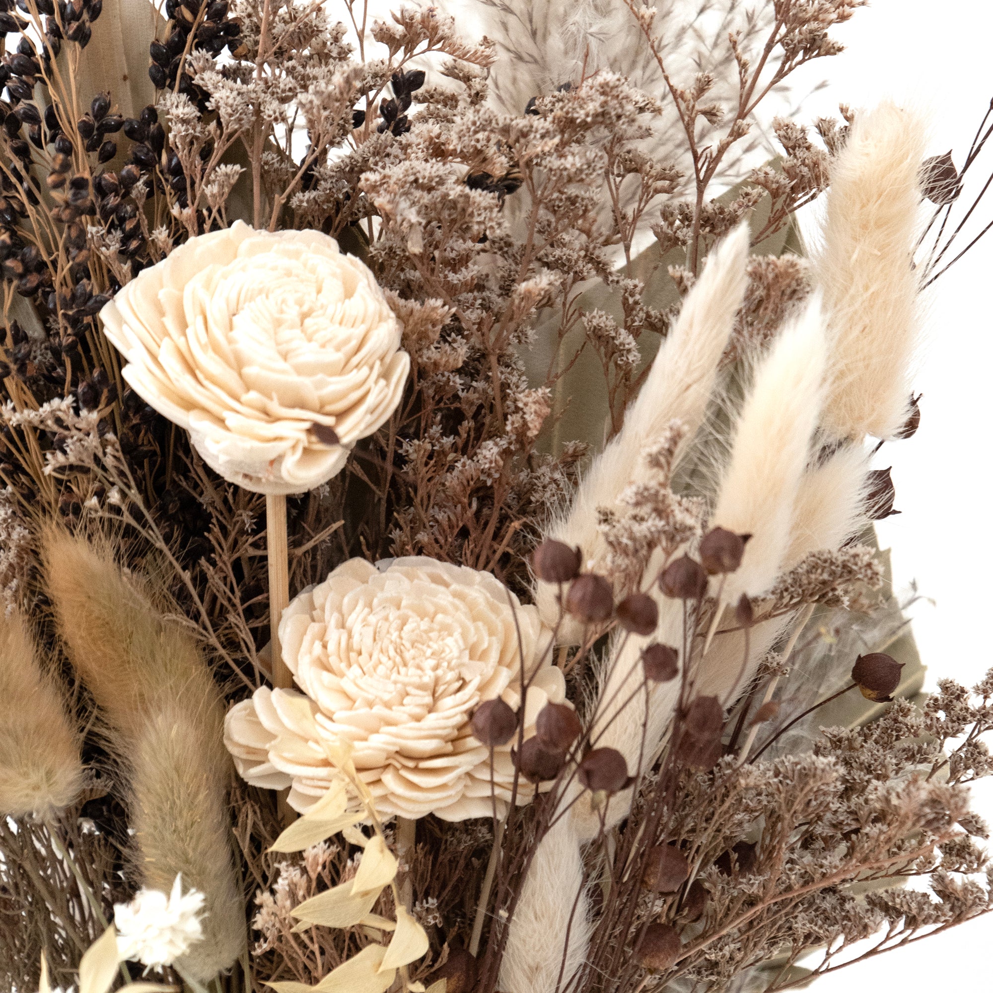 mixed white and tan dried floral bouquet against white background