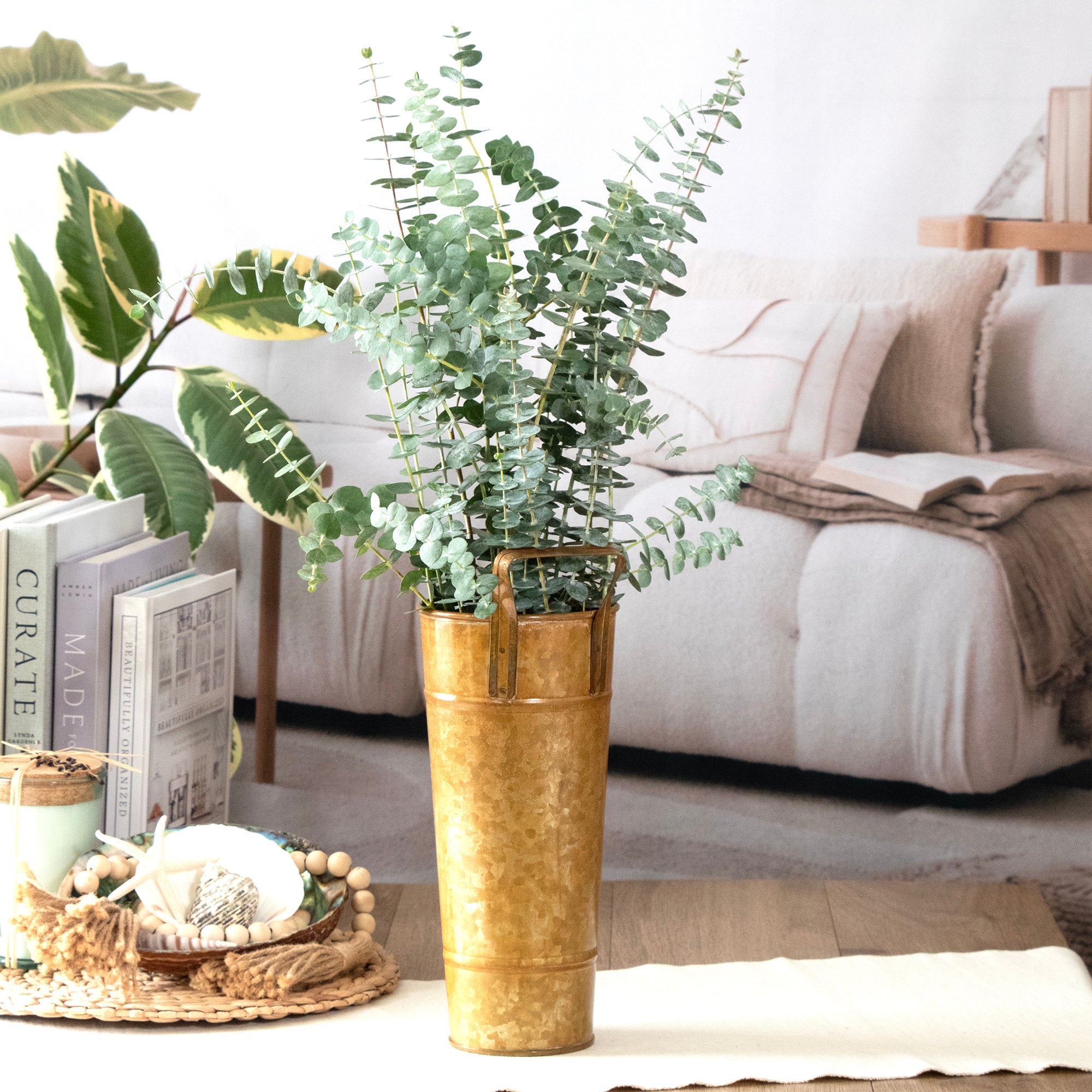Gold vase with greenery on a coffee table in a living room setting