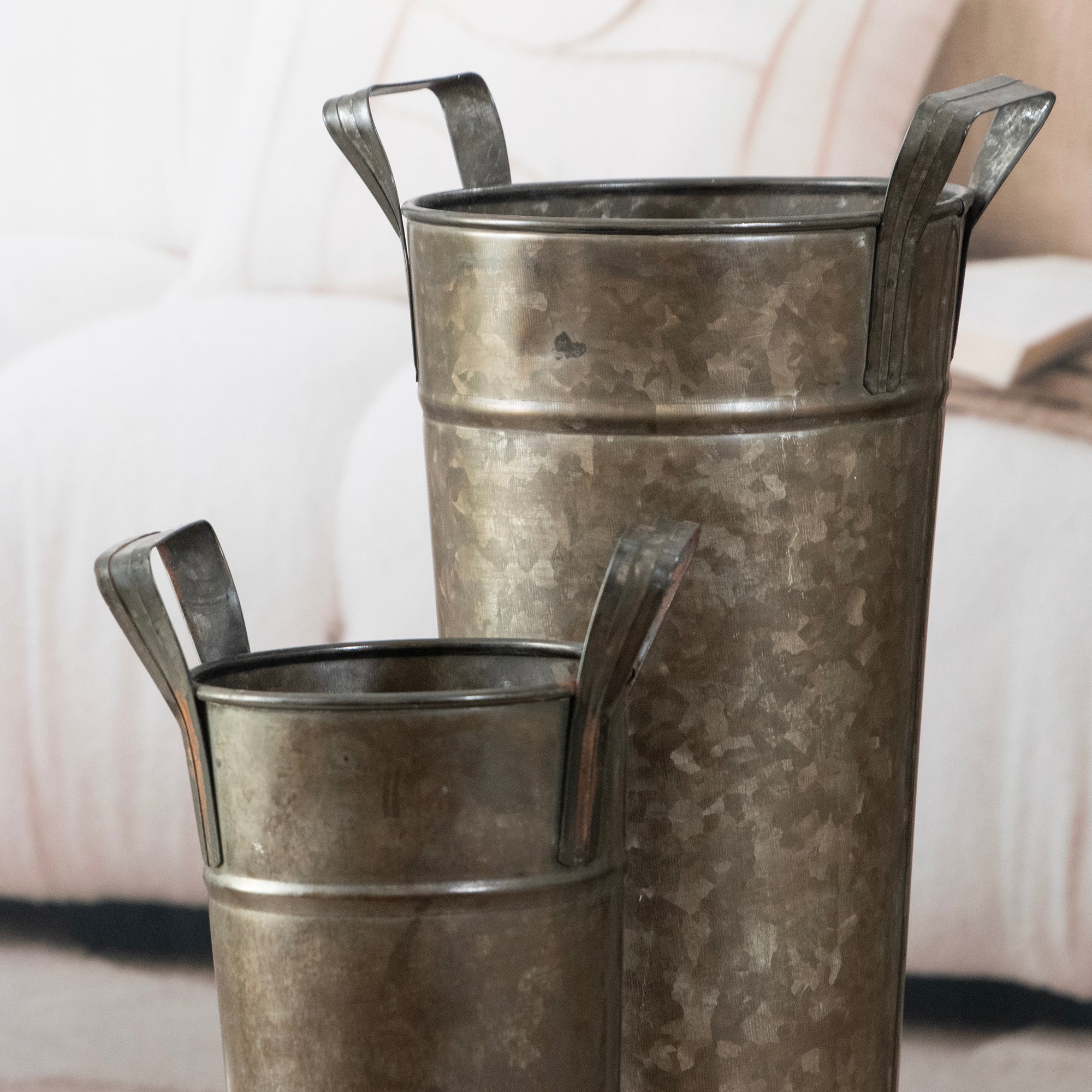 Two metallic buckets with handles on a light background