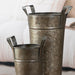 Two metallic buckets with handles on a light background