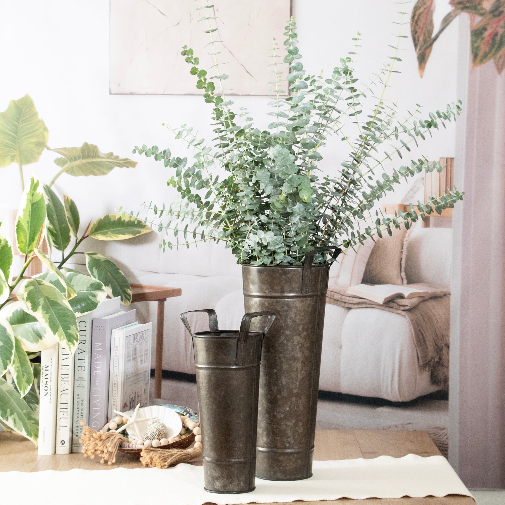 Decorative metal vases with greenery on a table in a living room setting.