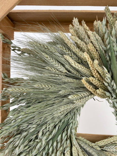 clustered mixed wheat wreath in wooden crate against white background