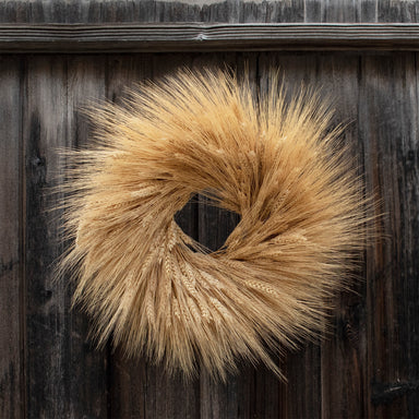 dried blonde wheat wreath against wood background