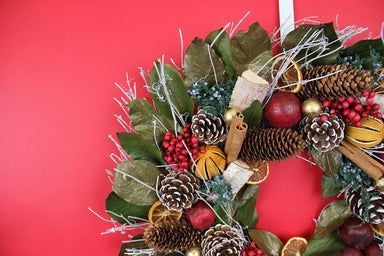 pomegranate citrus holiday wreath against red background